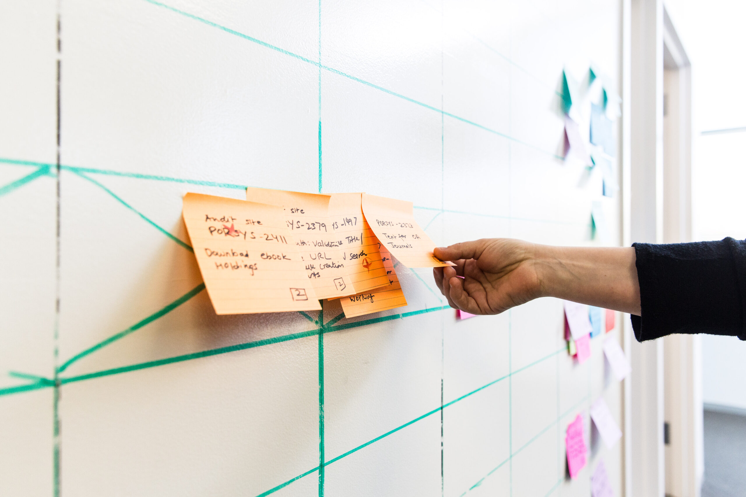 A colleague placing a sticky note on the whiteboard at ITHAKA's Princeton office